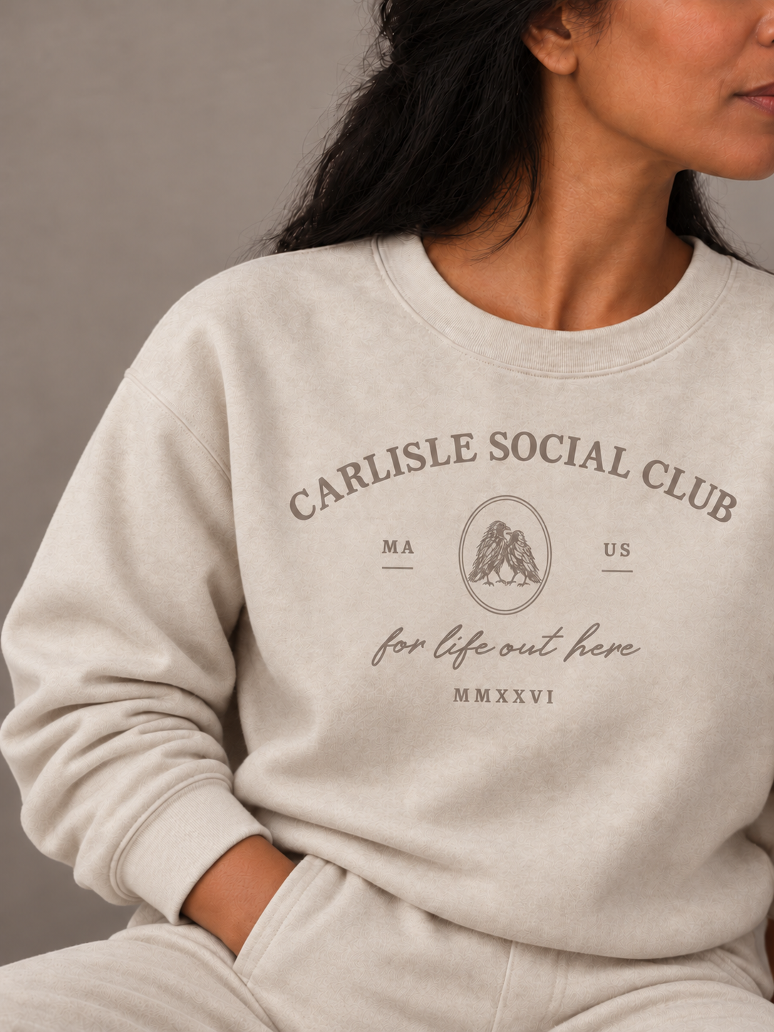 Model wearing the Sand Carlisle Social Club crest crew and matching pants, with her hand in her pocket